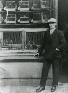 875121 Portret van L. Makkink, vogelkoopman, voor zijn winkel Varkenmarkt 29 in Wijk C te Utrecht.